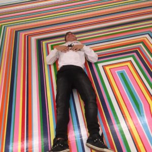 Young man lying on a colourful striped floor
