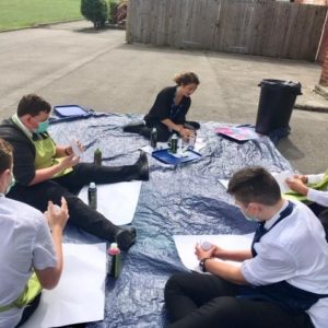 People sitting on the ground outside with paper and spray paint