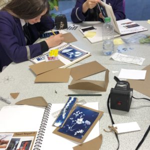 Two students at a table with lots of paper around them
